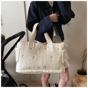 Detailansicht der gesteppten Wickeltasche mit Blumenstickerei und praktischen Seitentaschen