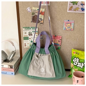 Detail of green and gray nylon drawstring tote bag with purple straps on a wooden desk