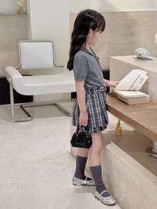 Fillette portant un sac à main à paillettes noires avec haut en tricot et jupe plissée