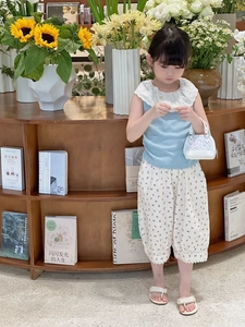 Fille portant haut bleu et pantalon fleuri avec sac à main coquillage à paillettes