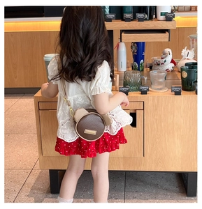 Toddler girl wearing a brown cartoon bear shoulder bag with plush ears in a cafe