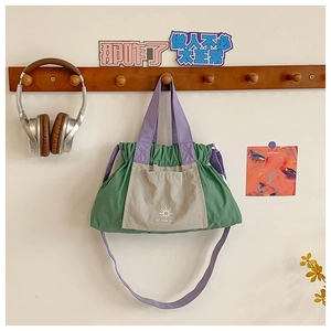 Detail of green kids tote bag with purple drawstring and front pocket showing sun pattern