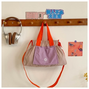 Detail of drawstring tote with orange straps, purple pocket and nylon texture