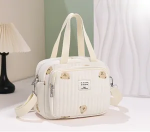 Détail d'un sac fourre-tout matelassé avec broderie d'ours et bandoulière réglable