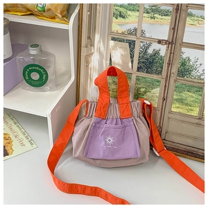 Detail of kids nylon crossbody bag with contrast orange strap and purple sun logo pocket