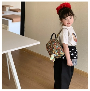 Toddler wearing a mini floral cartoon backpack with yellow plush toy charm accessory