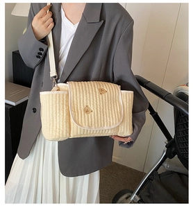 Détail du sac à langer matelassé beige avec broderie ours sur une poussette