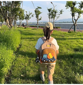 Outdoor shot of a kids' backpack with blue cement mixer graphic and decorative charm