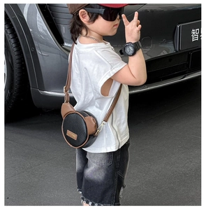 Detail of a round cartoon bear ear crossbody bag with leather texture and strap hook