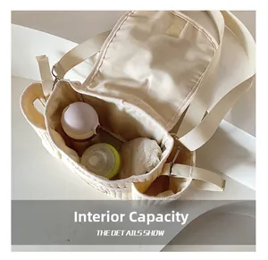 Détail du sac à langer matelassé crème montrant l'espace pour biberons et couches