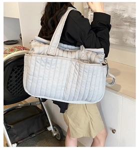 Gesteppte hellgraue Wickeltasche am Model für den Alltag und Reisen mit dem Kinderwagen