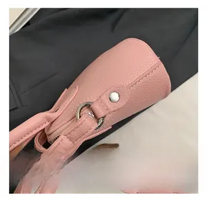Detail of pink pebbled leather bag featuring silver metal rings and zipper hardware