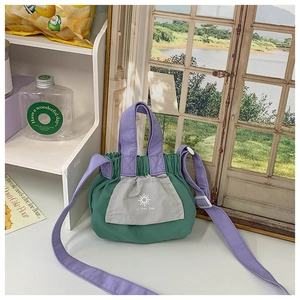 Detail of colorful kids' canvas bag featuring purple handles and green pleated fabric