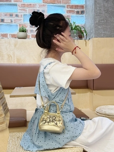 Mini sac à bandoulière doré à paillettes pour enfants présenté dans un cadre de vie réel