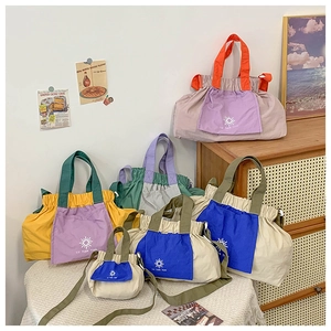 Detail of color-block nylon tote bags with drawstring closure and sun-shaped logo