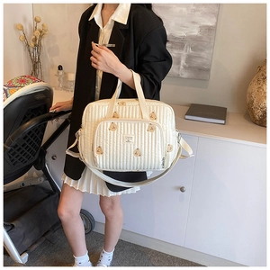 Quilted white diaper bag with brown bear embroidery showing hand-held and crossbody style