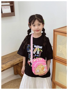 Detailed view of pink cartoon crossbody bag with adjustable strap on a young girl model