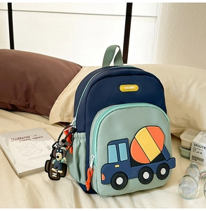 Detail of navy and green kids backpack featuring cartoon cement mixer and dog charm