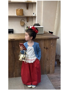 Girl's blue knit cardigan and red polka dot wide-leg pants set with a gold mini handbag