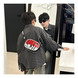 Mirror view showing a child wearing a stylish red and black crossbody bag with plaid shirt