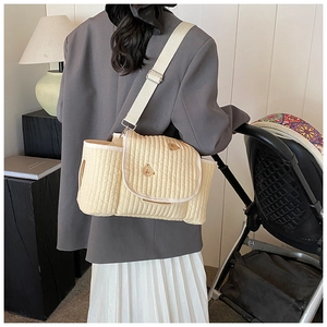 Gros plan du sac à langer matelassé beige avec broderie ours et large bandoulière