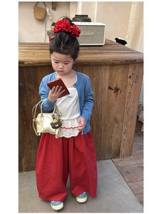 Flat lay of girl's blue knit cardigan with red polka dot pants and cute gold handbag