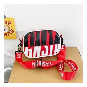 Detail of red and black crossbody bag with wide nylon strap and fashion logo text