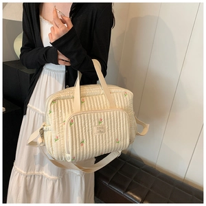 Quilted beige diaper bag featuring embroidered pink tulips and a stylish shoulder strap