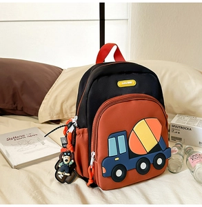 Close-up of kids backpack featuring a cartoon concrete mixer truck and cute dog charm