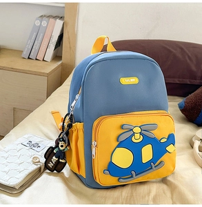 Detail of blue and yellow kids backpack with cartoon helicopter and doll pendant