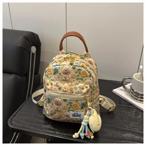 Close-up of beige mini backpack with 3D floral embroidery and plush chick charm