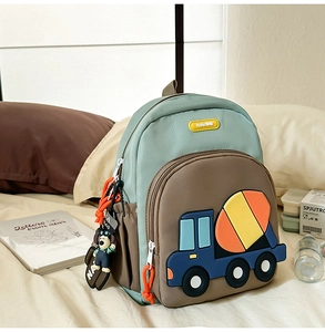 Detail of mint green and brown school bag with cartoon cement mixer truck and charm