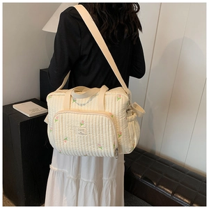 Detailed side view of quilted cotton diaper bag with elegant floral embroidery patterns