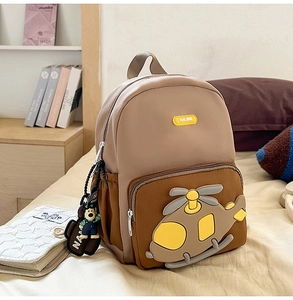 Close-up of a cartoon helicopter design and bear plush charm on kids' backpack