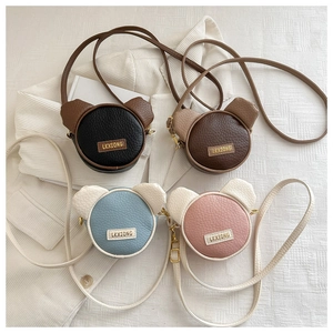 Detail of four colorful mini bear-shaped crossbody bags in premium litchi grain leather