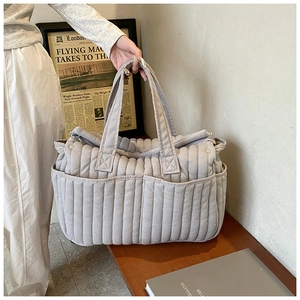 Detail der grauen gesteppten Wickeltasche mit Seitentaschen und strukturiertem Stoff