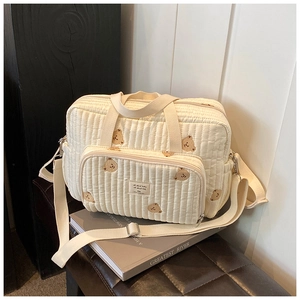 Detail of quilted off-white diaper bag with brown bear patterns and durable handles