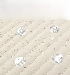Macro view of soft waterproof quilted fabric with water droplets on a beige diaper bag