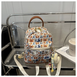 Detail of cartoon fox print backpack with plush moon charm on a modern shelf display