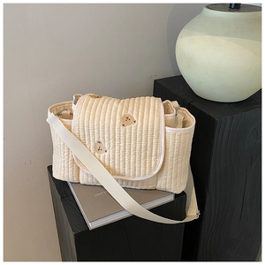 Détail du sac à langer matelassé avec broderie d'ours brun et large bandoulière crème