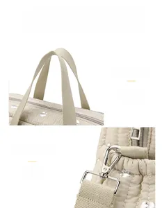 Detail of cream quilted diaper bag with silver dots, sturdy handles and metal hooks