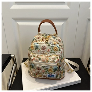 Detail of 3D embossed bear and floral pattern on cream mini backpack with gold zippers