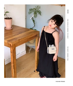 Detail of a beige woven crossbody bag for girls featuring a silver metal bow accent