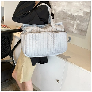 Detail der grauen gesteppten Wickeltasche mit Seitentaschen und strukturiertem Stoff