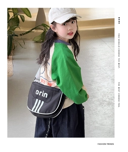 Close-up of black kids messenger bag featuring white stripe design and adjustable strap
