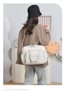 Close-up of beige quilted diaper bag with silver dots and adjustable shoulder strap