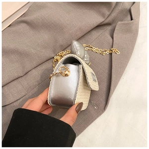 Detail of mini straw woven crossbody bag with metallic leather and silver bow decoration