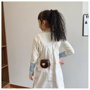 Détail d'un mini sac bandoulière en cuir marron avec fermoir cœur doré et chaîne