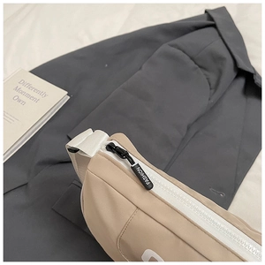 Detail of beige nylon crossbody bag with fashion zipper and white letter strap