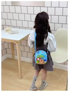 Rear view of a child wearing the blue Capybara cartoon crossbody bag with printed beach motifs